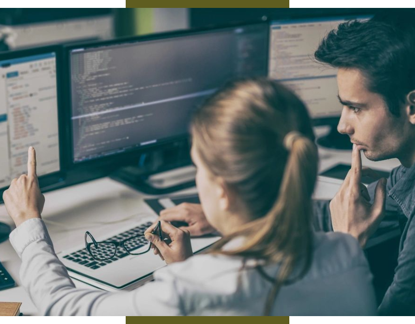 Two people sitting at a desk with computers.